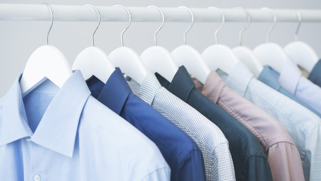 Assorted blue shirts hanging on wooden hangers